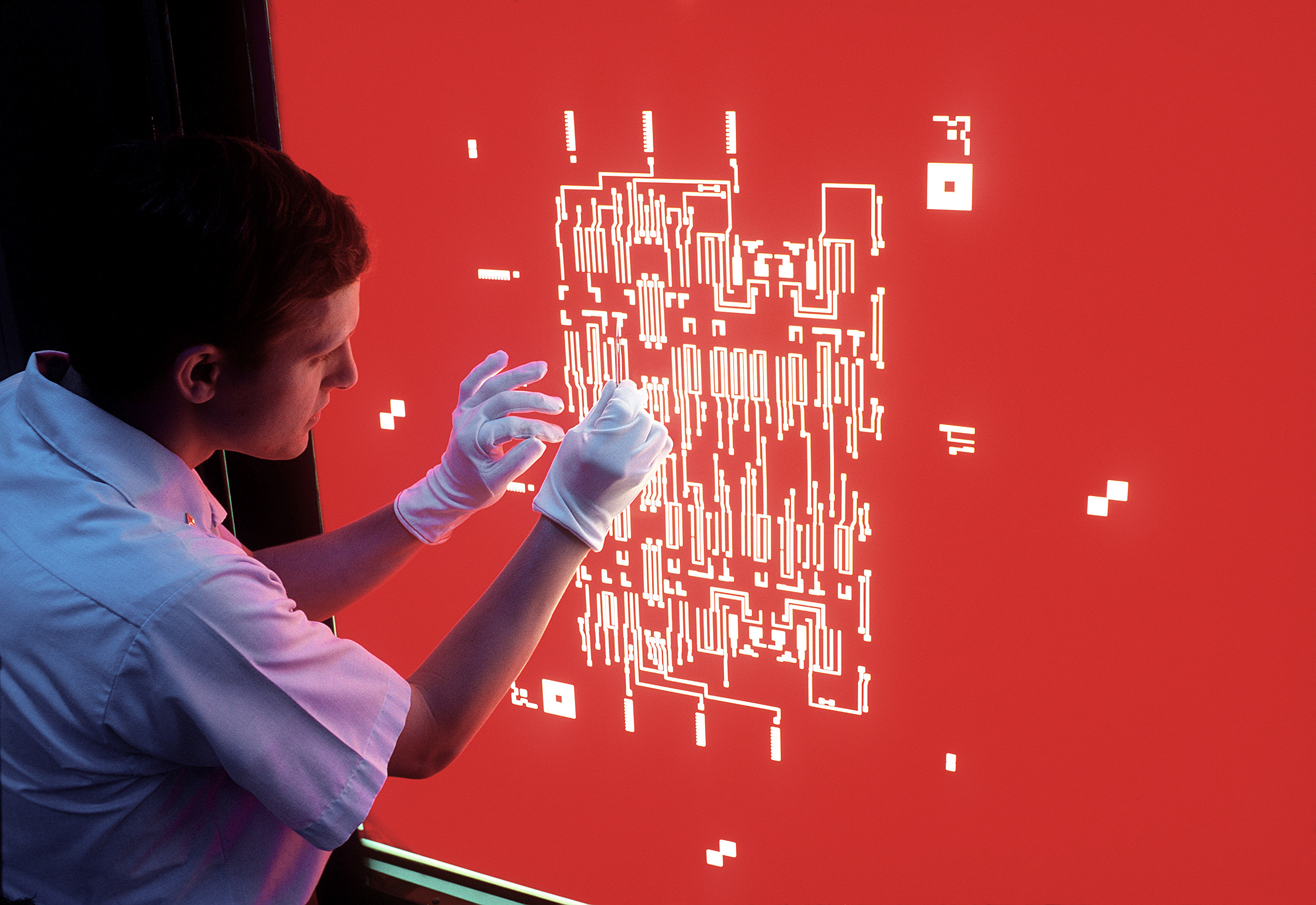 Technician hand-cutting a circuit layout on rubylith film, 1980